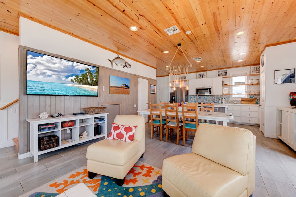 Relax in your stylish open-concept space where rustic wood ceilings meet coastal charm, complete with comfortable seating and full kitchen for memorable gatherings.