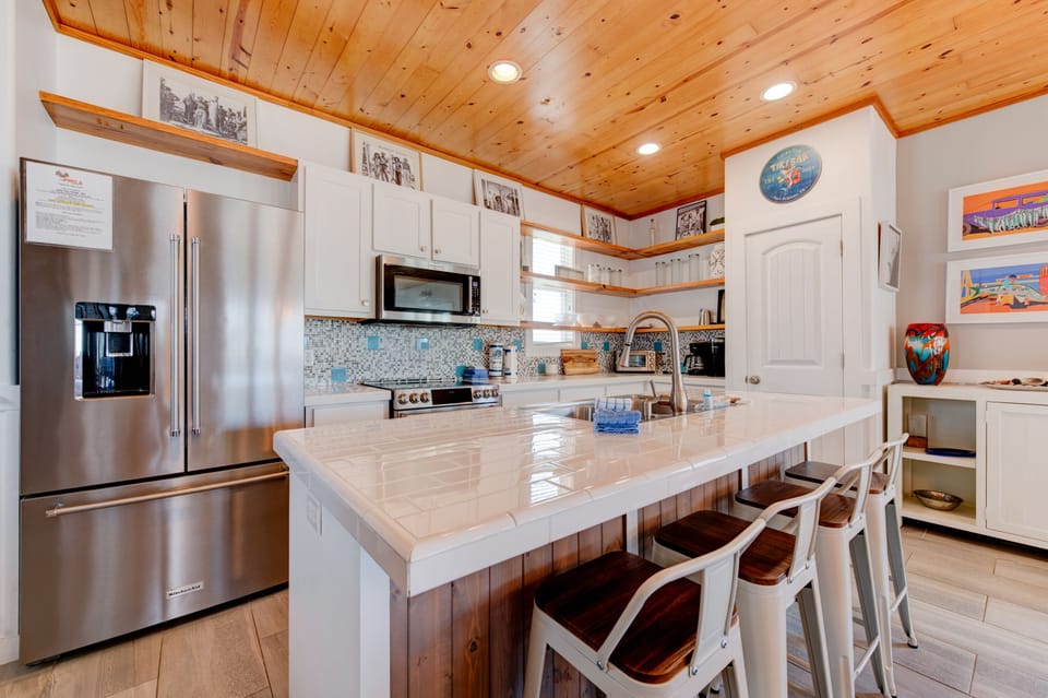 Your chef-worthy kitchen awaits with gleaming countertops, stainless appliances, and warm wood ceiling—perfect for creating memorable meals together.