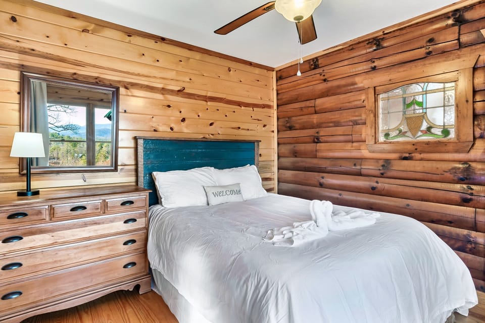 Main level queen bedroom with unique stained glass window to the living area