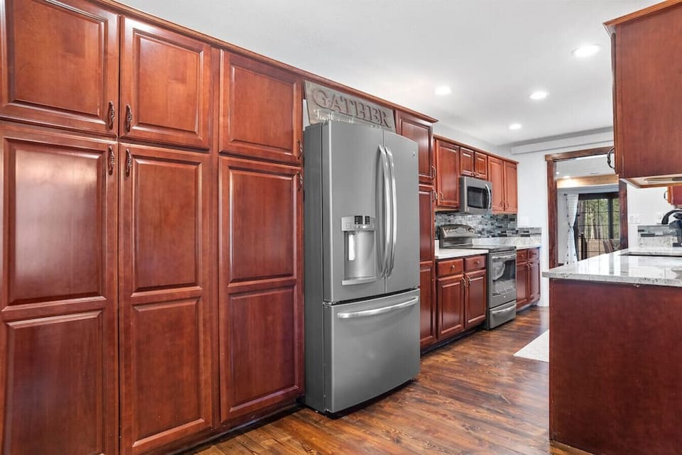 Spacious kitchen showcases abundant cabinet storage and a gleaming stainless-steel refrigerator.