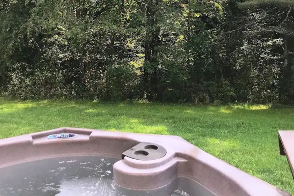 Hot tub with forest, meadow and sky view