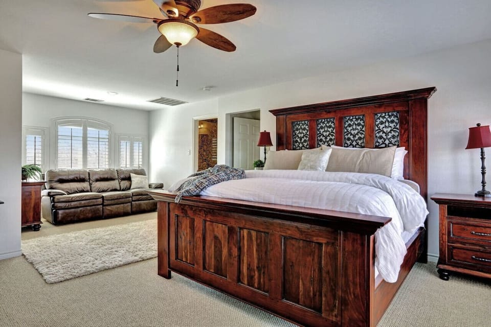 Recharge in the top-level primary bedroom with a king bed, smart TV, desk, sofa, and large closet—quiet comfort near Lake Travis in Spicewood, TX.