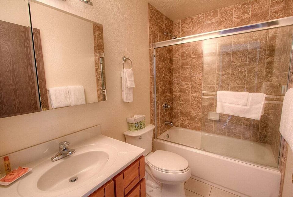 Bathroom with a tub and shower behind sliding doors.