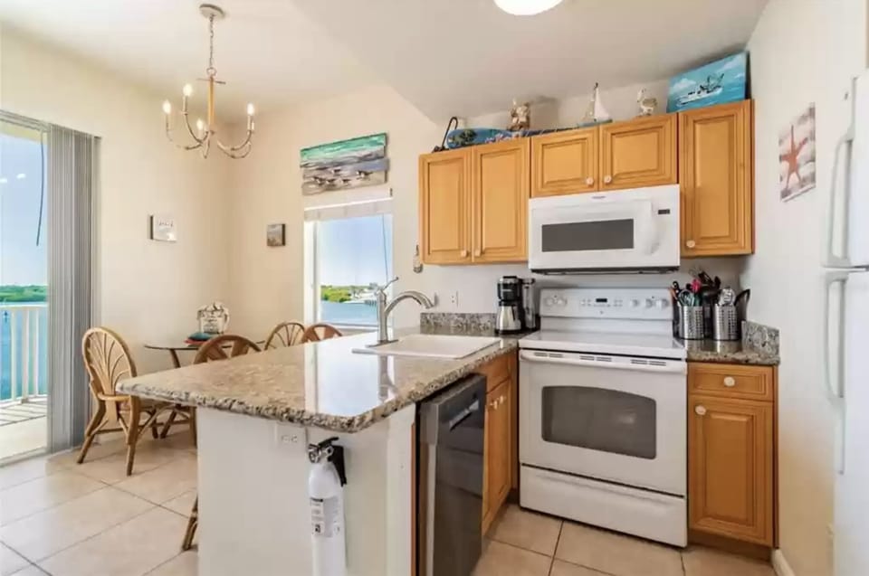 Kitchen with utensils, microwave, oven, stovetop, dishwasher and coffee maker.