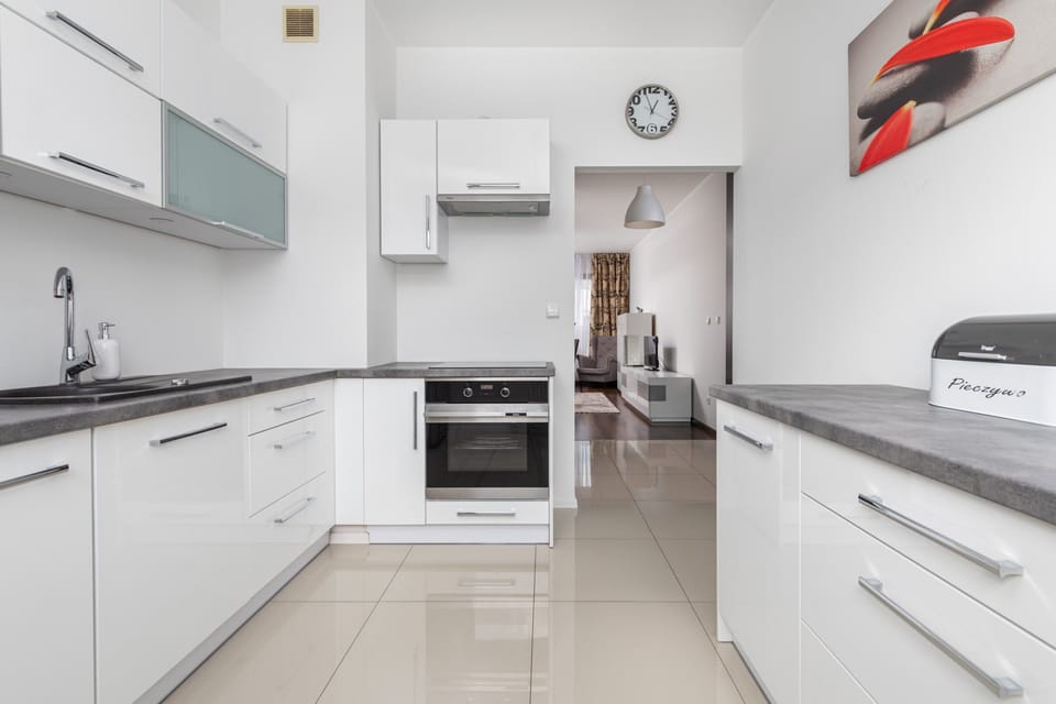 Modern kitchen with white cabinets, built-in oven, and sleek appliances.
