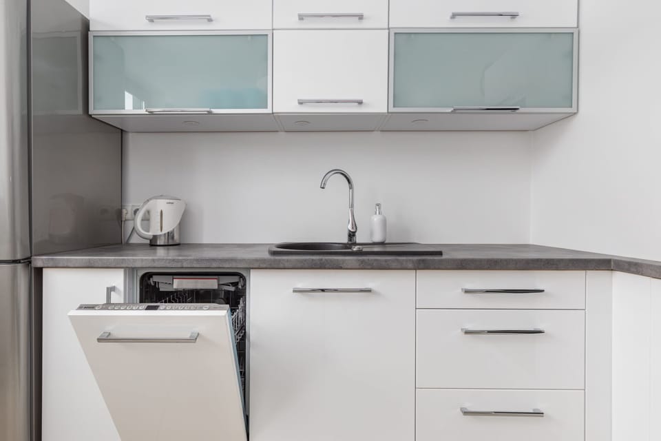 Modern kitchen with white cabinets, built-in oven, and sleek appliances.
