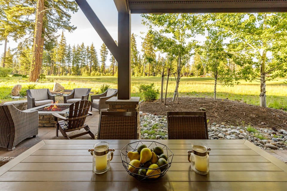Open-air dining under a wood pergola with lush views and comfortable seating.