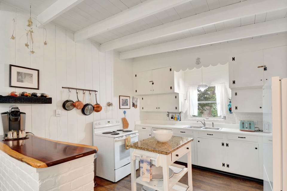 Kitchen – Vintage Style with Modern Essentials - With original cabinets, a deep farmhouse sink, and everything you need for real meals, this Jekyll Island kitchen is a cheerful basecamp between beach runs and convention days.