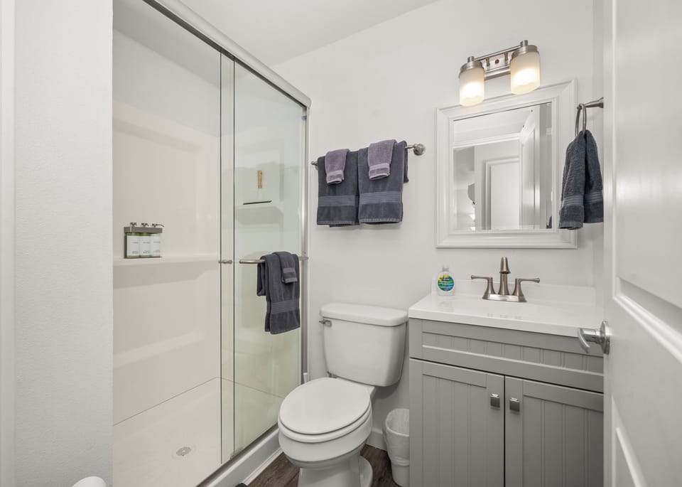 Bright modern bathroom with glass shower and stylish gray vanity