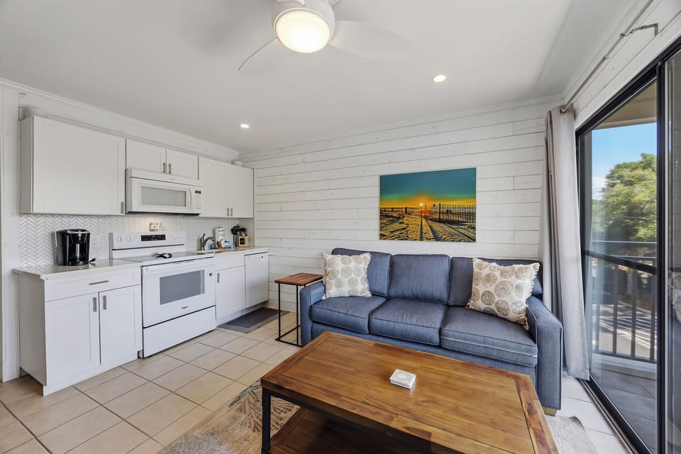 Updated living area with a new queen sleeper sofa, full-size appliances, and ocean-view balcony access.
