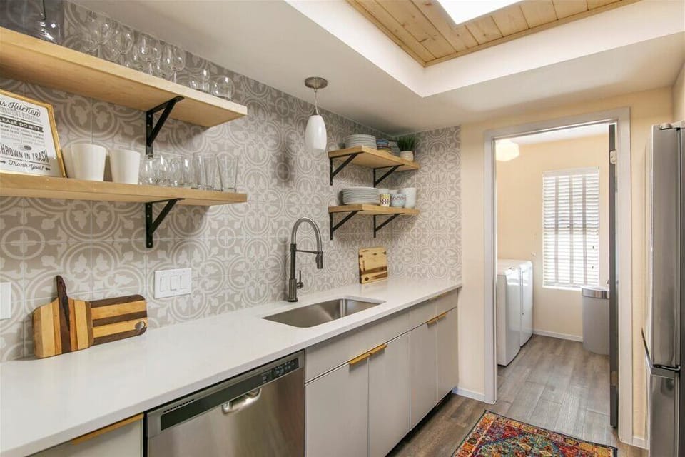 Updated fully stocked kitchen with open shelving and full-size dishwasher.