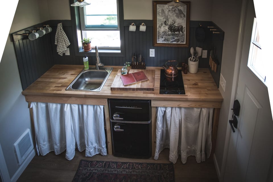 Kitchenette in bathhouse with 2 burner stovetop and mini fridge. 