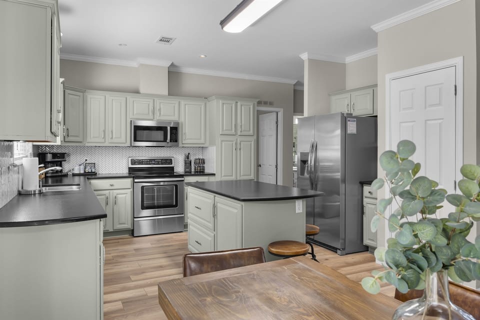 Granite countertops, stainless steel appliances, a dining table seating six, and a bar that seats three