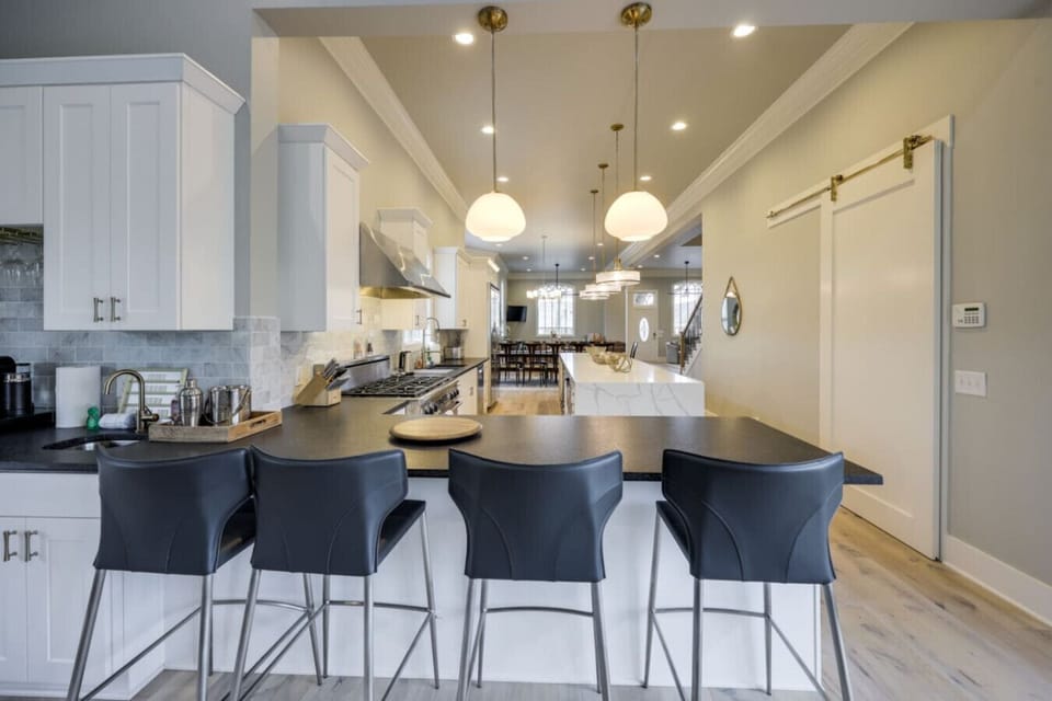 Kitchen with dark bar stools at a large island, pendant lights, and a barn door