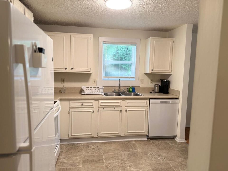 Bright, spacious kitchen with white cabinetry, tile backsplash, and full appliances — cook with ease in this well-designed space.