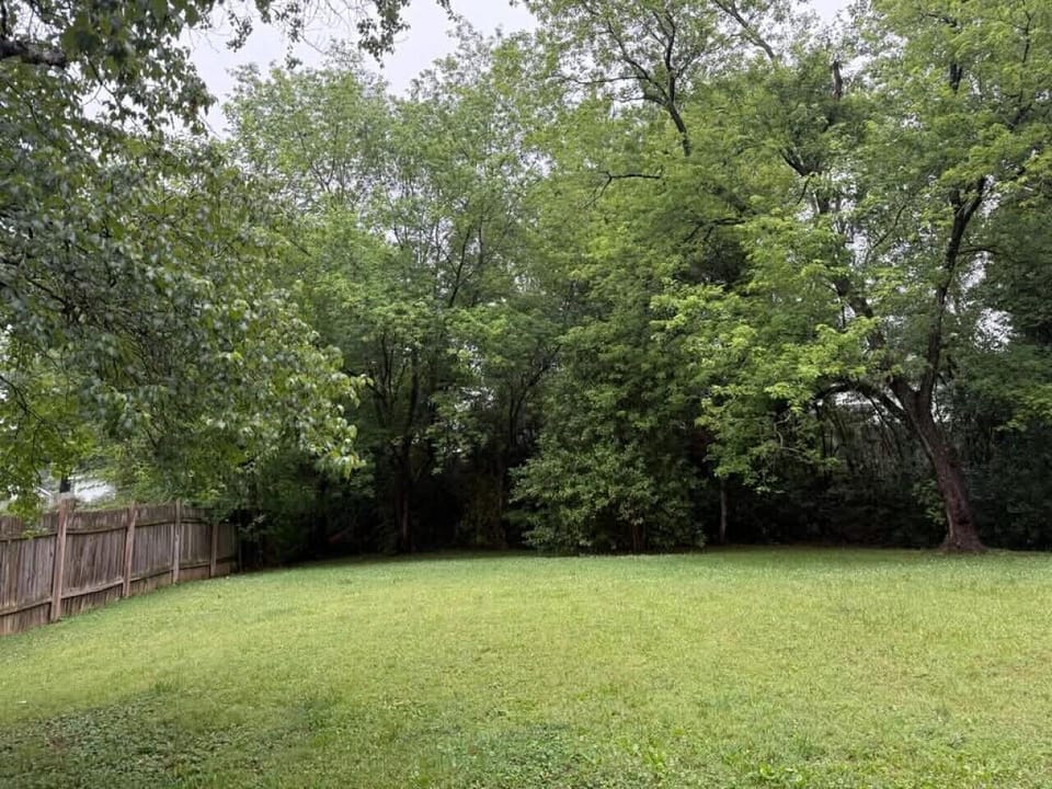 Private fenced backyard surrounded by mature trees — enjoy your own outdoor green space, perfect for morning coffee or an evening breeze.