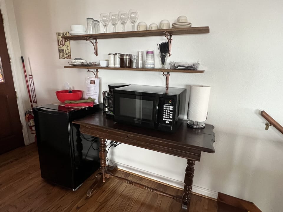 Kitchenette with fridge, microwave, coffee, and water bottles.