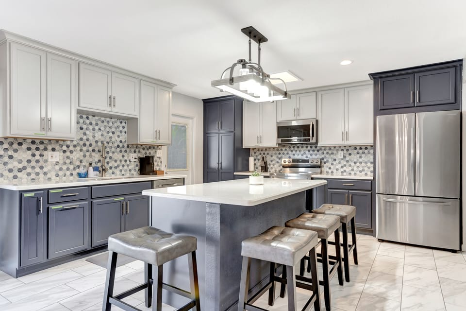 Kitchen features two-tone navy and white linen cabinets with granite countertops