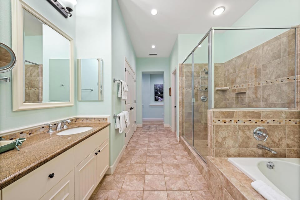 Ensuite primary bathroom with double vanity, walk-in shower, and soaking tub