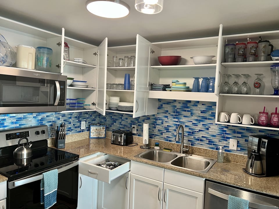 Beautiful blue backsplash; Cabinets with new pots & pans, dinnerware & flatware