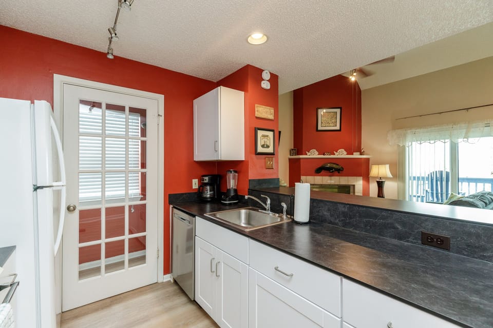 Your fully equipped kitchen features modern appliances and warm red accent walls, perfect for preparing meals during your stay.