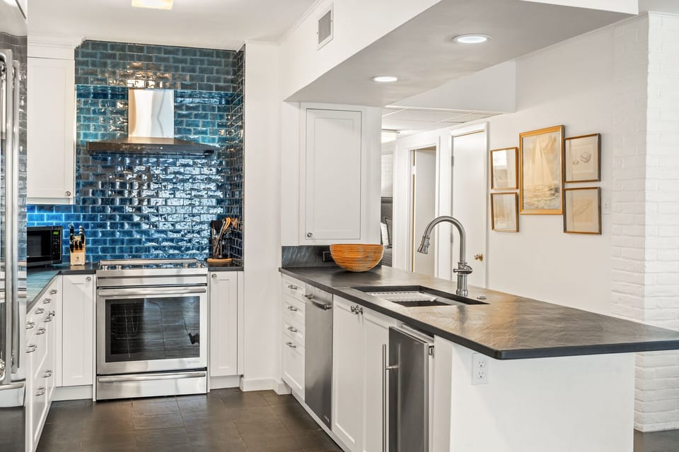 Your gourmet kitchen features stunning blue tile backsplash, sleek countertops, and premium appliances for creating memorable meals.