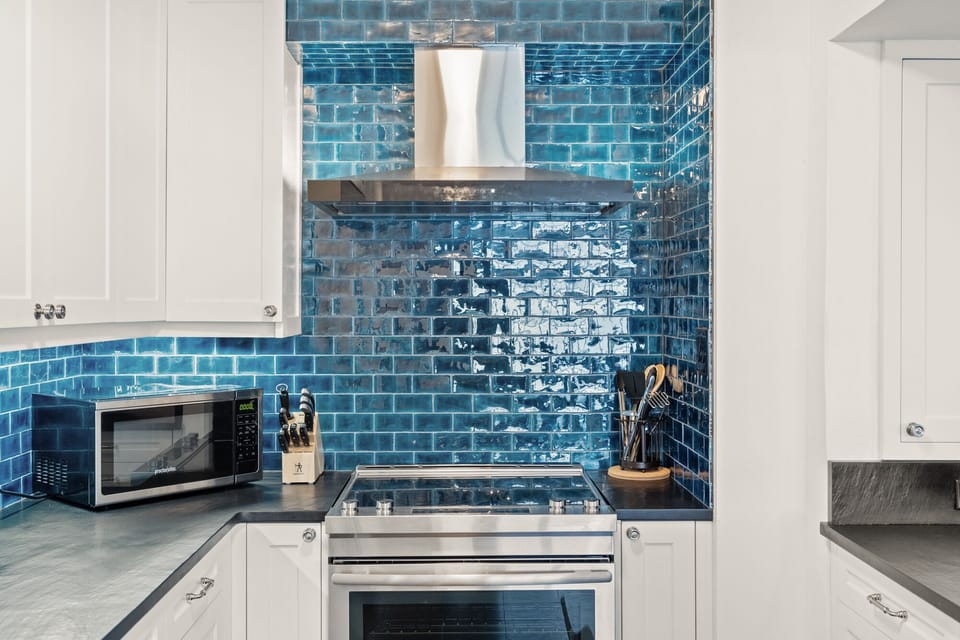 Cook with style in this stunning kitchen featuring vibrant blue subway tiles and modern appliances perfectly arranged for your culinary adventures.