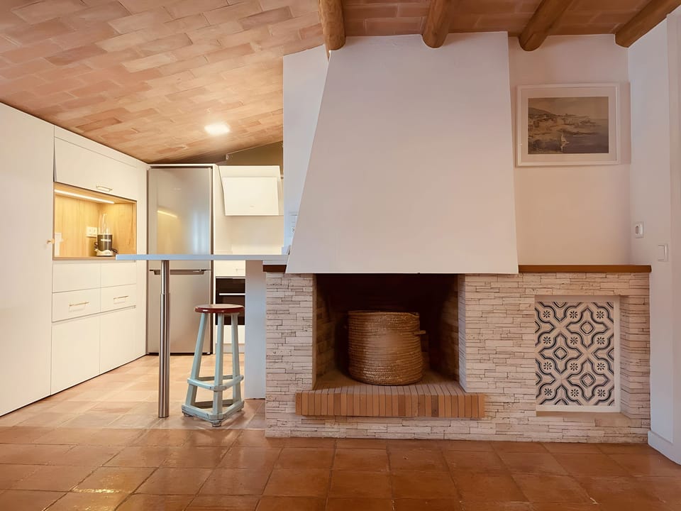 This spacious and modern kitchen features a unique fireplace. The warm terracotta tile floor adds a touch of traditional charm to the modern design.