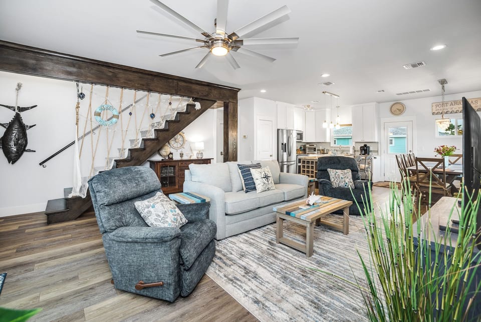 Sink into comfortable coastal vibes in this open living space where your vacation memories unfold beneath soaring ceilings and nautical charm.