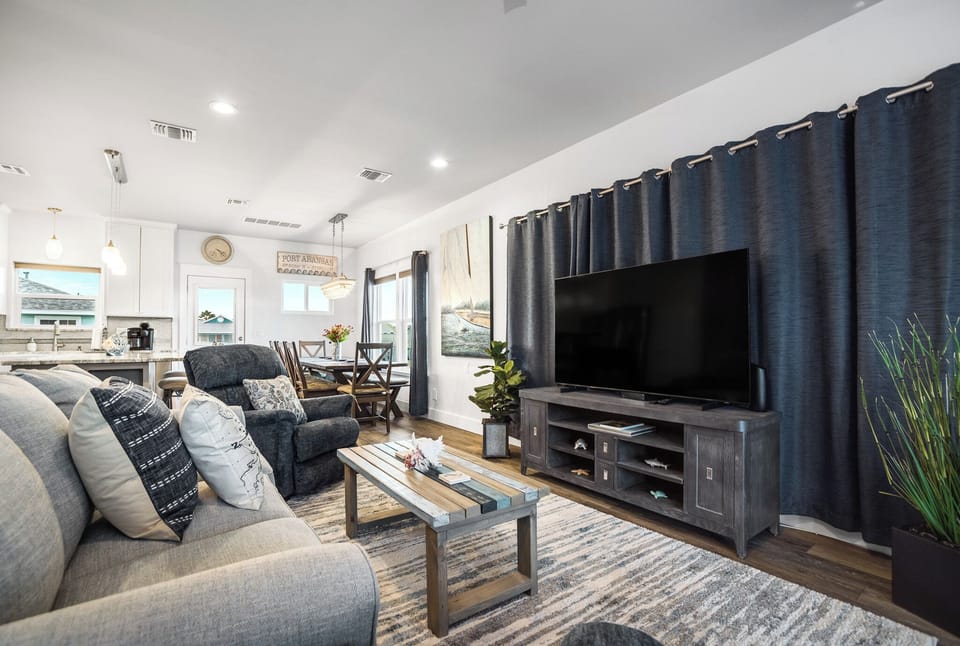 Unwind in your spacious living area with plush seating, entertainment center, and stylish coastal décor that creates the perfect atmosphere for relaxing evenings.