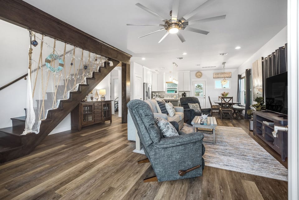 Relax in your spacious open-plan living area with coastal charm, featuring cozy seating and rustic wood details.