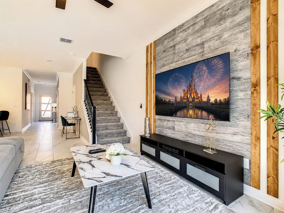 Modern living area with large TV and rustic wood accent wall