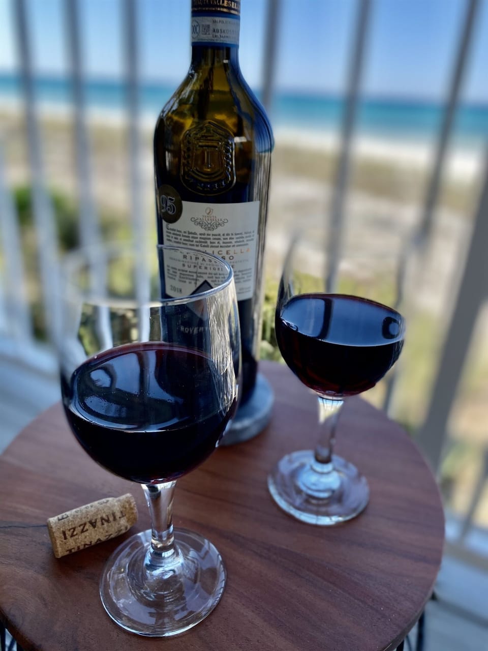 Sip rich red wine on your private balcony as turquoise waters shimmer beyond—the perfect romantic evening retreat.
