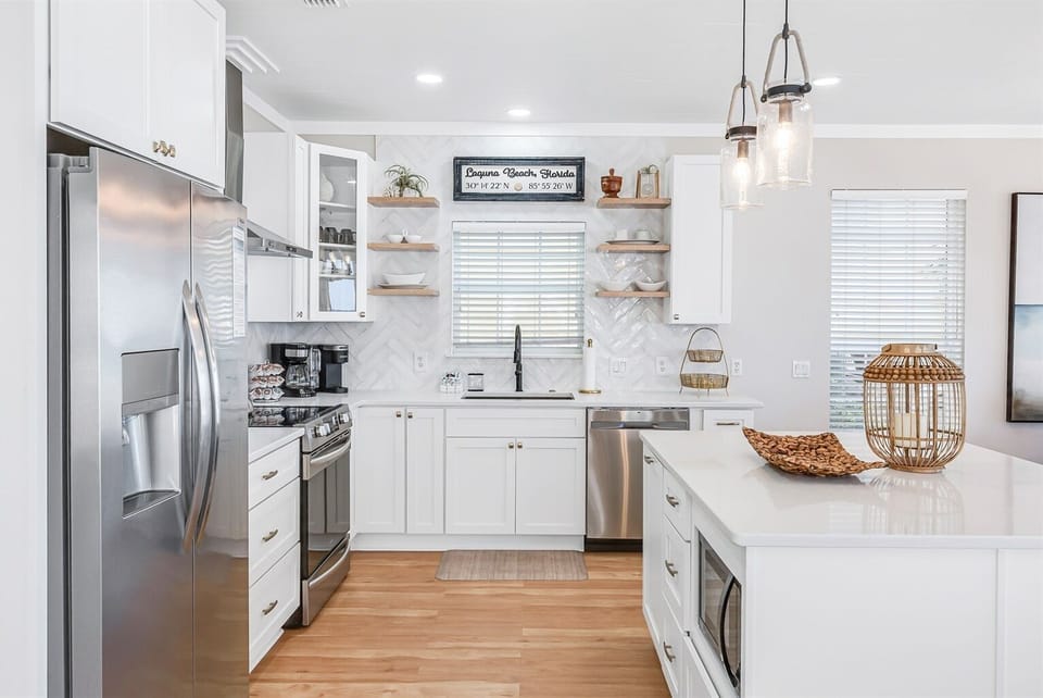 Cook your favorite meals in this bright, fully-equipped kitchen with gleaming white cabinets, stainless steel appliances, and a spacious island for gathering.