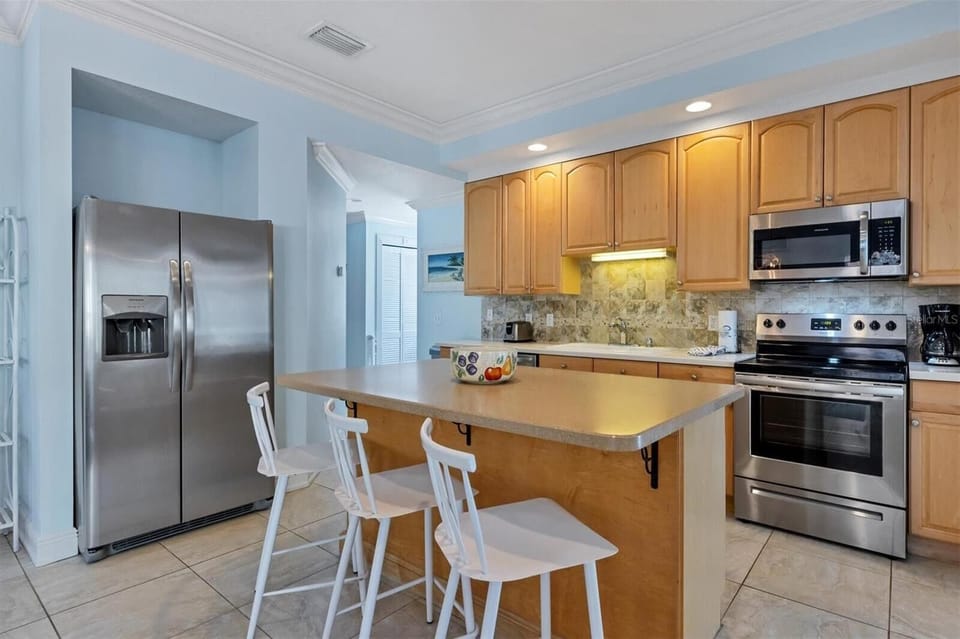 Wide-angle kitchen view showing appliances, counter space, and bar seating