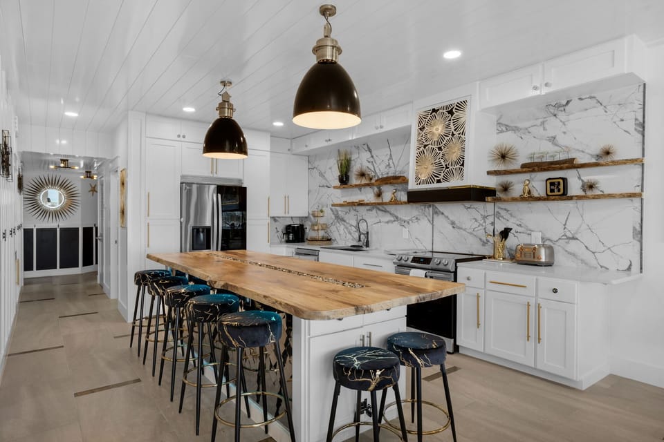 Your spacious kitchen features marble backsplash, live-edge island seating for eight, and brass accents creating perfect gathering space.