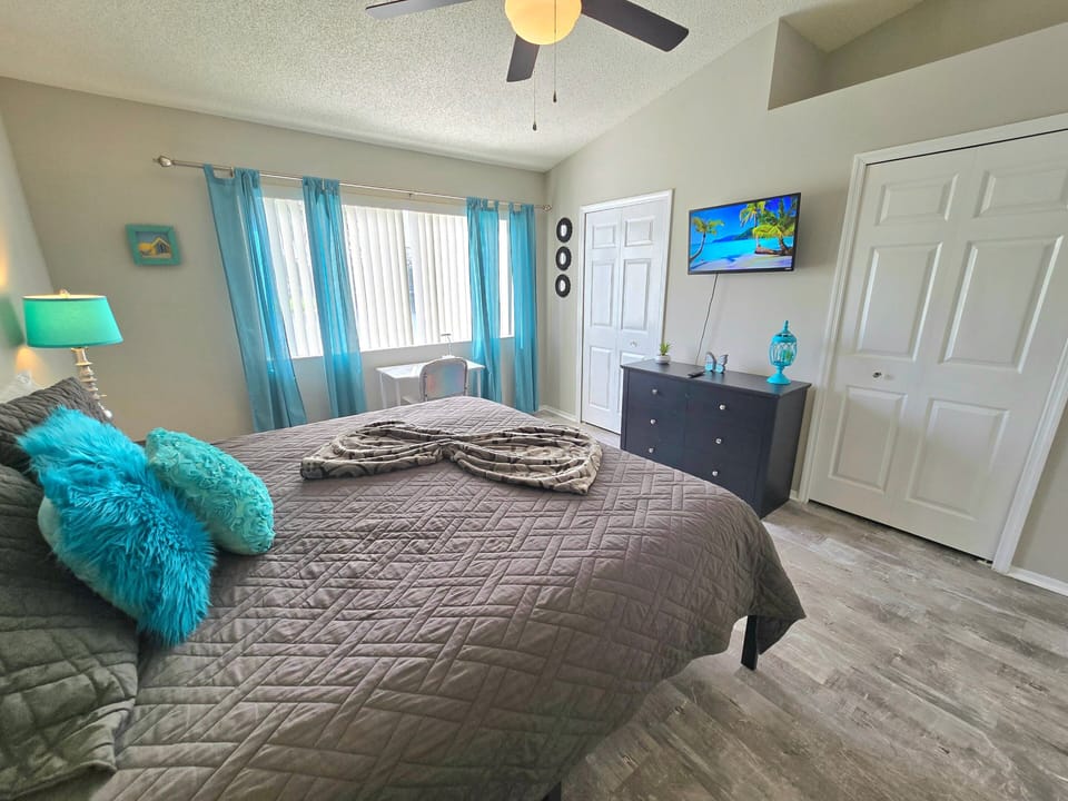 Your guest bedroom has a wall-mounted TV and teal curtains — everyone gets a private, comfortable space.