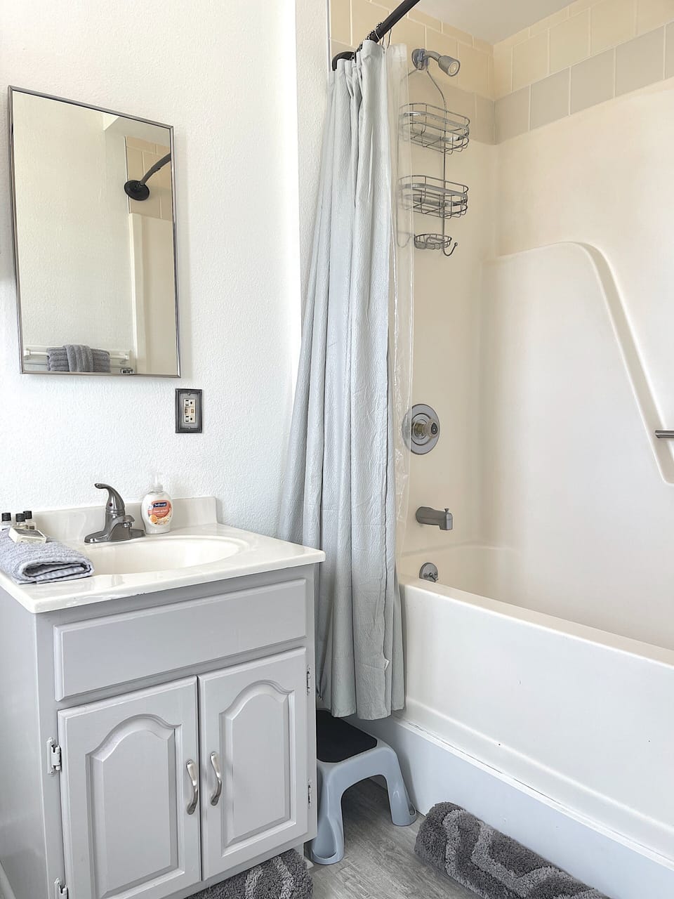 Bathroom with tub/shower combo. Tall step into shower, shower has grab bar and step stool.