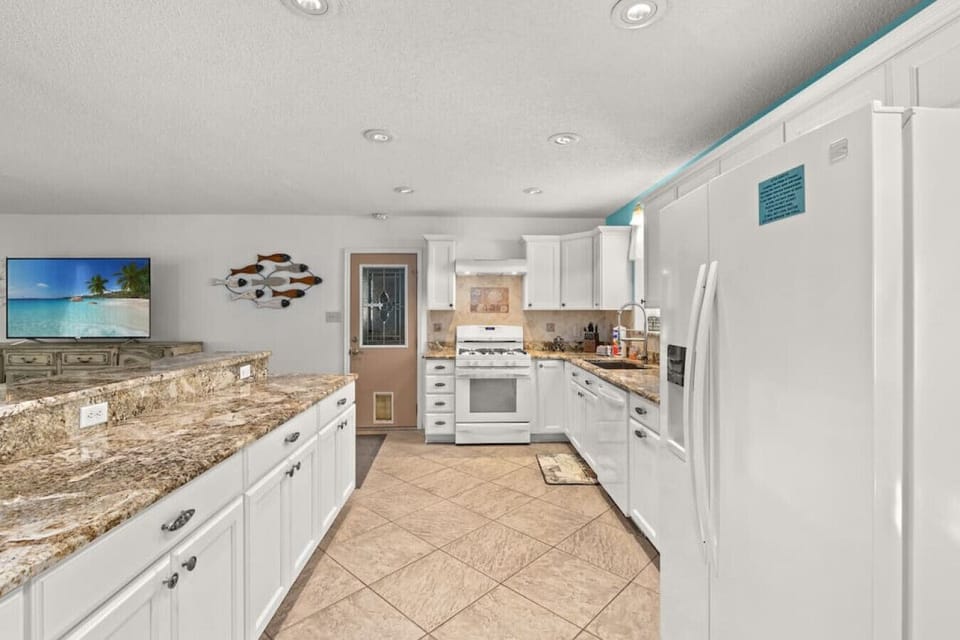 Large, open kitchen with granite counters, breakfast bar, gas range, & fully-stocked for guests to whip up a meal