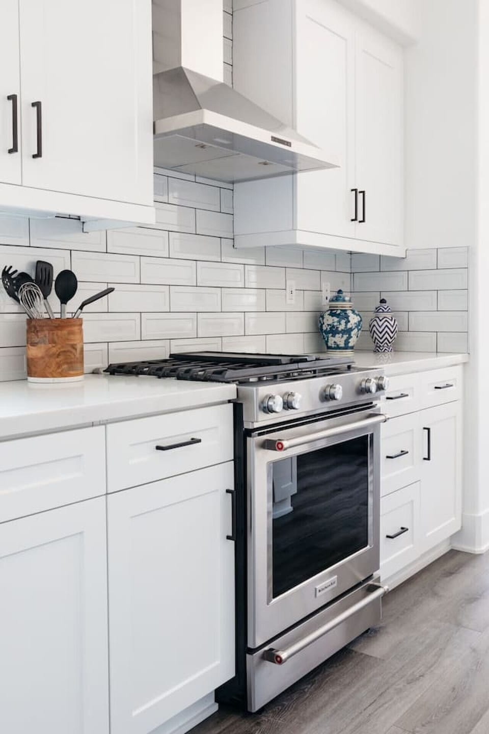 Modern kitchen w/ stainless range, tile backsplash & clean white cabinetry