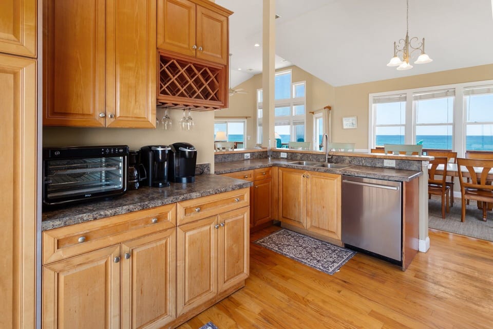 The modern, fully equipped kitchen includes a corner bar with seating for five, a wine rack, and all the appliances needed to prepare delicious meals.