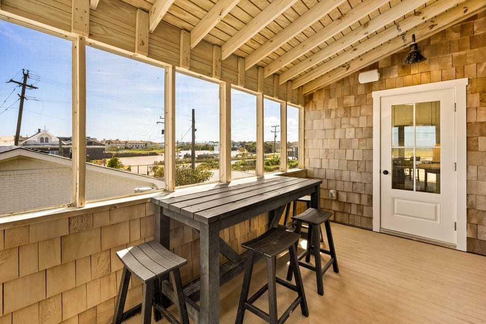The screened-in porch offers a perfect setting for alfresco dining or enjoying the ocean breeze without the worry of insects.