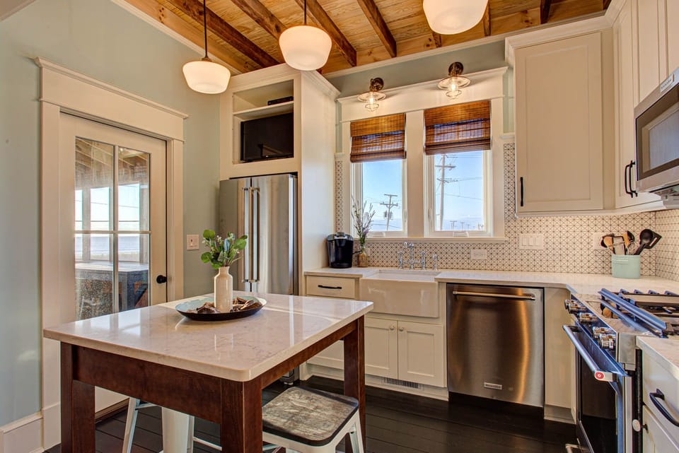 The modern kitchen features stainless steel appliances, a fully stocked prep area, and an island bar with seating for casual meals.