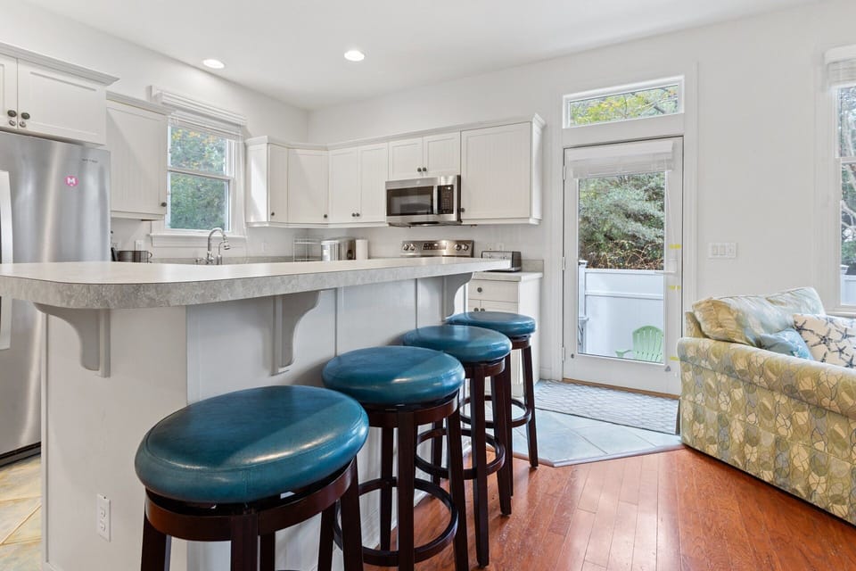Bottom-Level Kitchen: Fully stocked kitchen with white cabinets, modern appliances, and ample counter space for preparing OBX favorites.