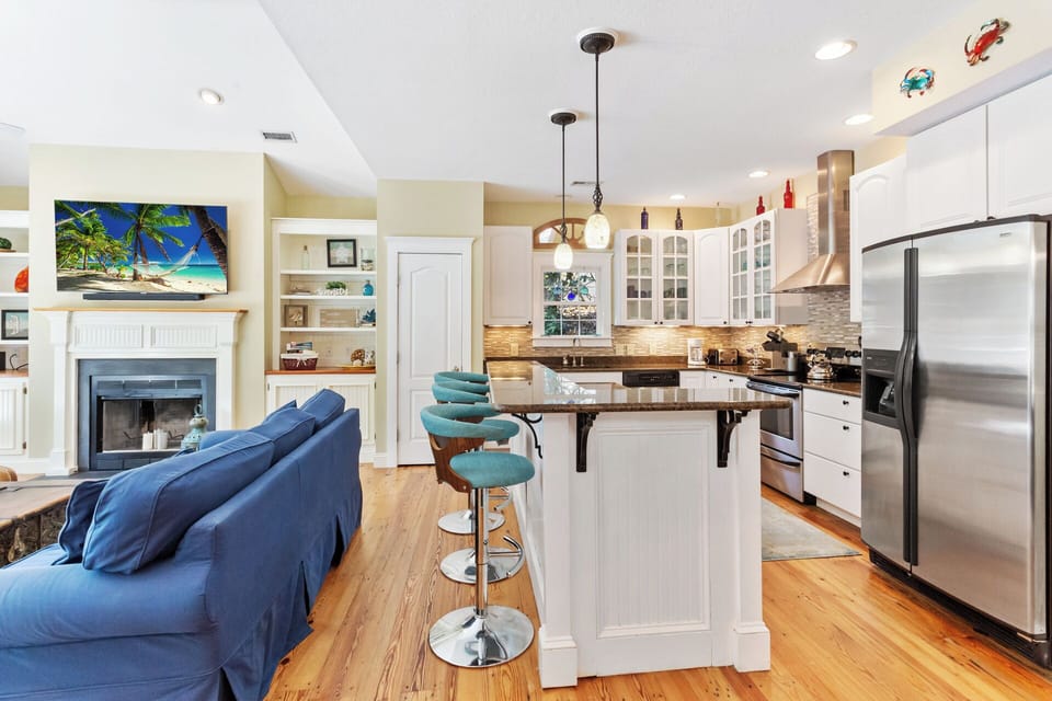 In the kitchen, you'll find additional bar seating for 3, as well as sleek stainless steel appliances and white cabinets with open glass doors.