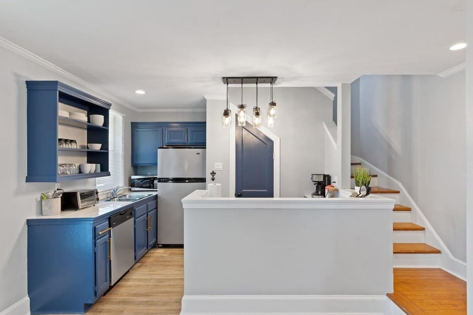 Stylish kitchen w/ navy cabinetry, pendant lights & plenty of counter space.
