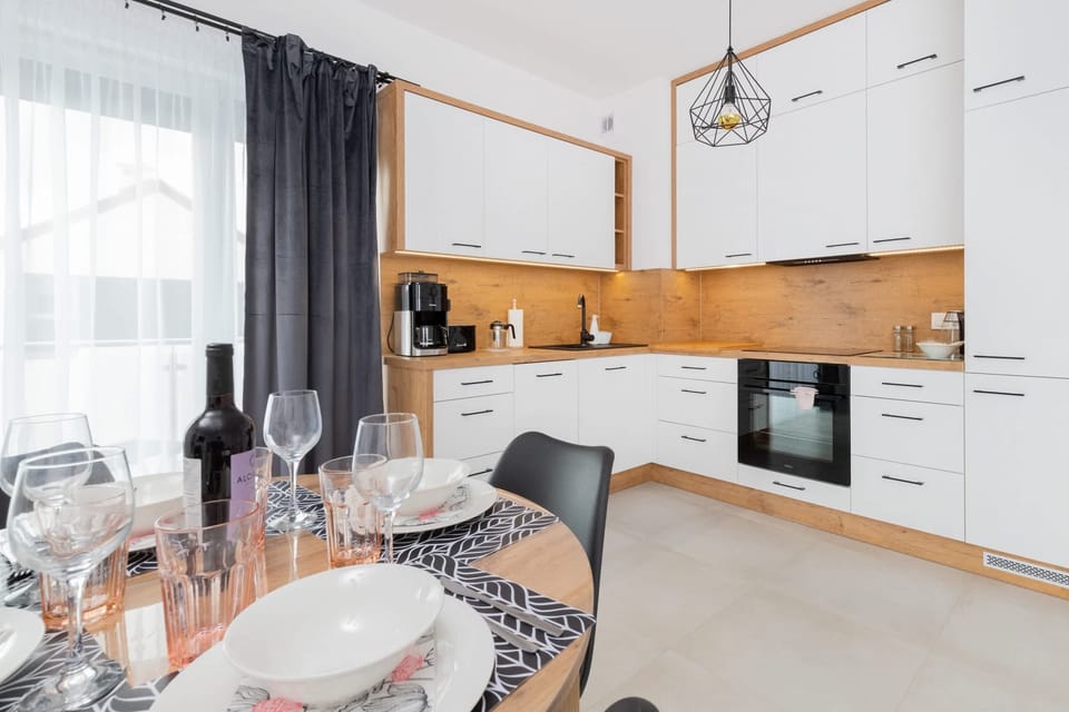 A modern kitchenette with wooden cabinets, white fronts, and appliances like an oven and stovetop, blending functionality with minimalism.