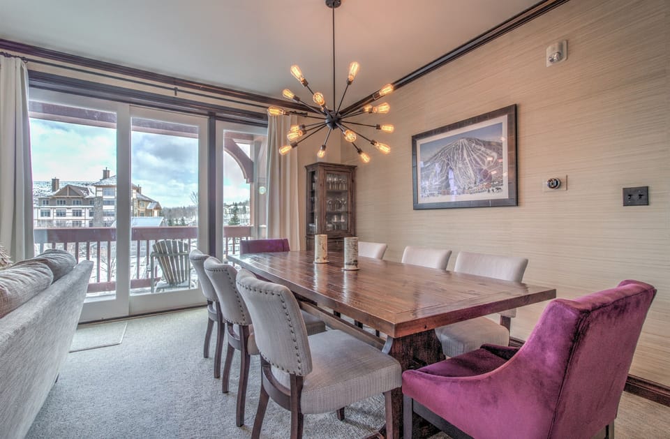 - Scenic dining space with plush seating and wide glass doors to the balcony - Warm lighting and panoramic mountain views fill the room - Perfect for après-ski meals, sunset dining, and cozy indoor evenings