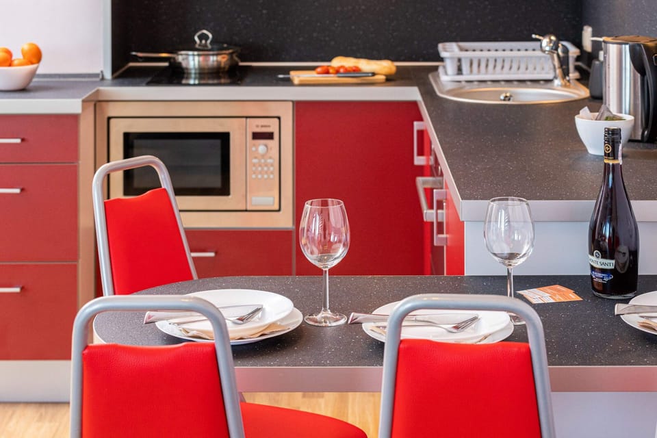 Dining area with a table, red chairs, and a bottle of wine ready for a cozy meal.
