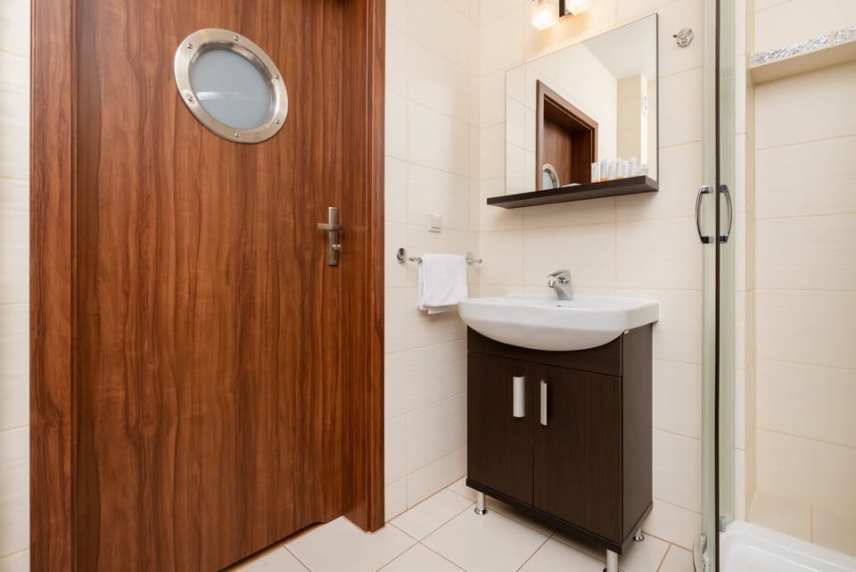 Modern bathroom with a wooden door, white sink, and functional storage cabinet.
